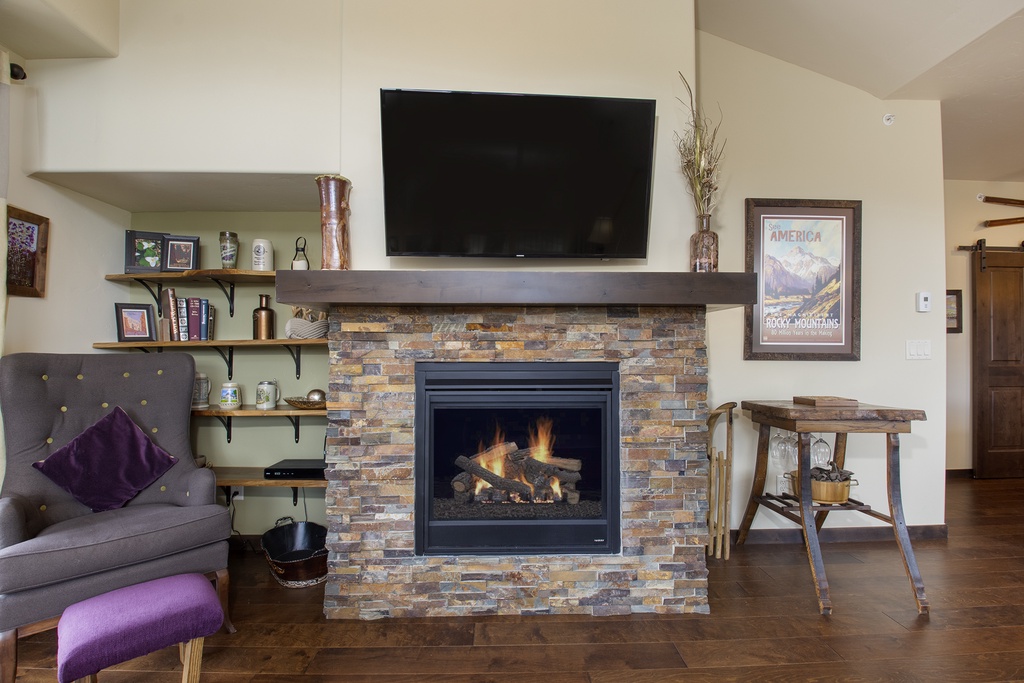 Cozy up by your crackling stone fireplace with mountain views on the wall-mounted TV above the rustic mantel.