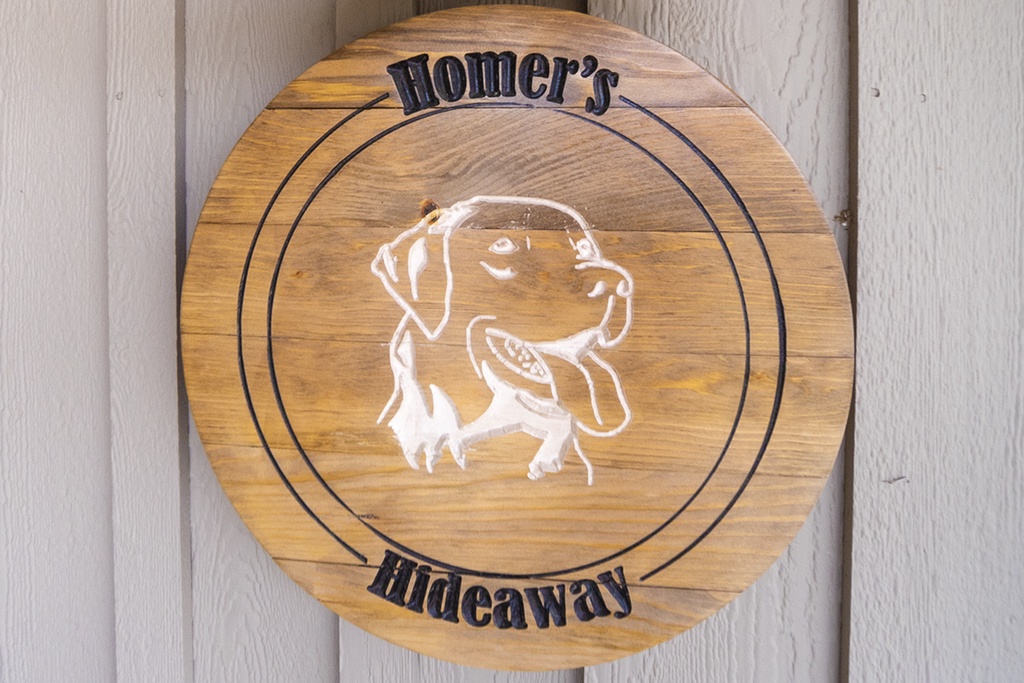 A warm wooden sign featuring Homer's Hideaway marks this pet-friendly retreat, promising cozy moments ahead.