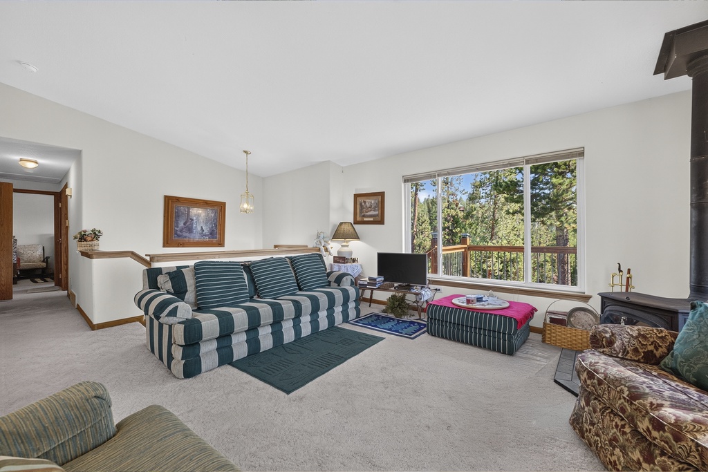 Unwind in your peaceful living room where natural light pours through windows framing tall pines. Gather by the cozy fireplace and enjoy the quiet retreat of the forest outside.
