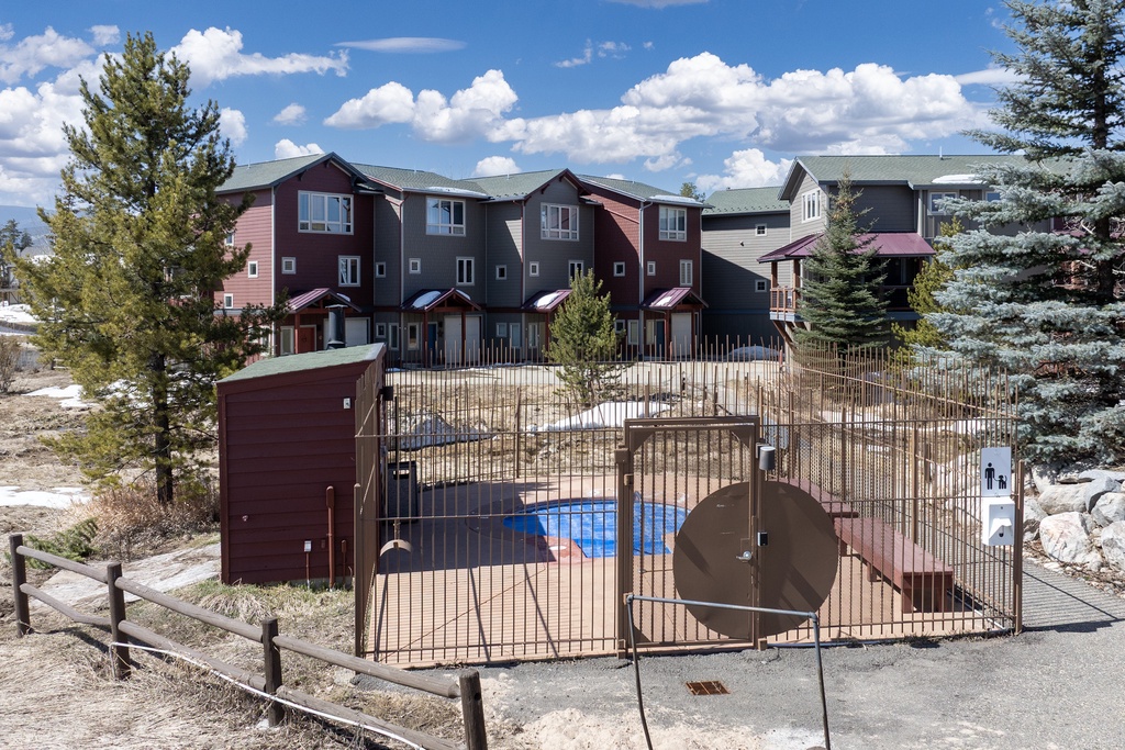 Mountain vacation rental complex featuring townhomes with fenced pool area surrounded by mature evergreen trees.