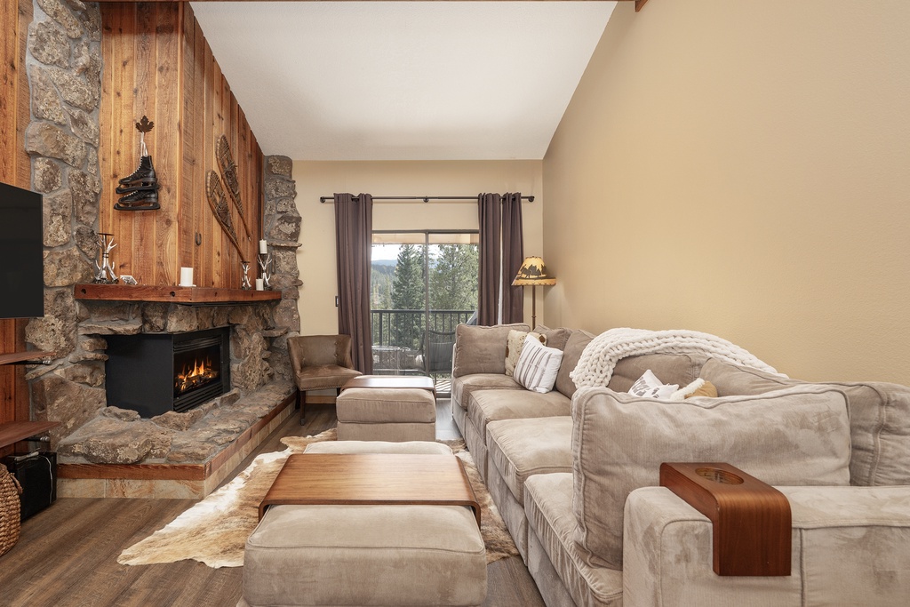 Curl up on plush seating by your crackling stone fireplace, watching flames dance while forest views frame your cozy mountain retreat.