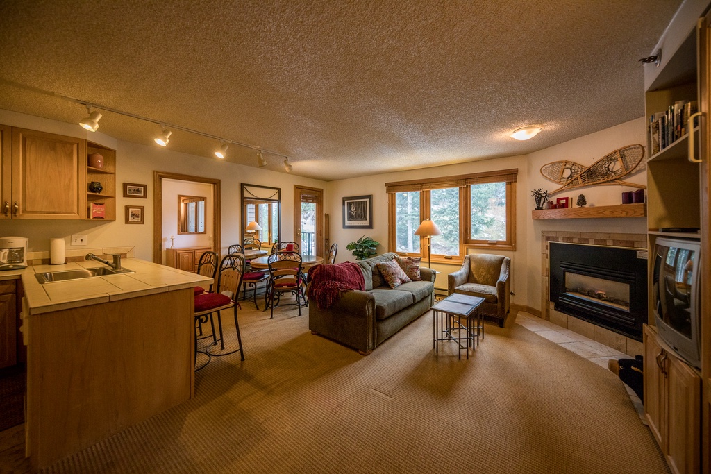 Relax in your cozy open-concept retreat where warm wood tones and a crackling fireplace create the perfect atmosphere for memorable evenings.