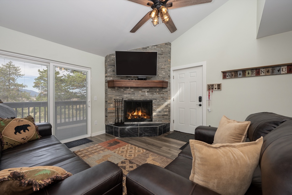 Cozy up by your crackling fireplace while enjoying mountain views through floor-to-ceiling windows in this inviting living space.