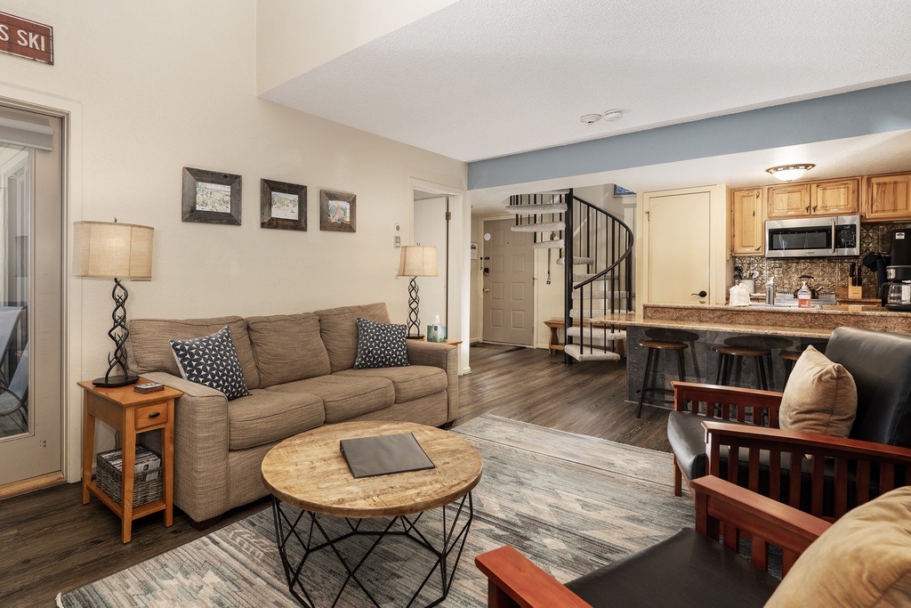 Settle into your cozy open-plan living space where warm wood tones and plush seating create the perfect mountain retreat atmosphere.