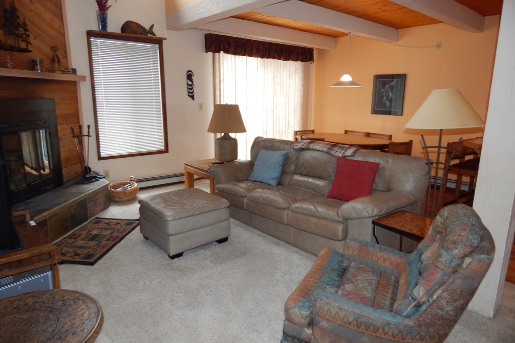 Sink into plush leather seating by the fireplace, where warm lighting and exposed beams create your perfect mountain retreat sanctuary.