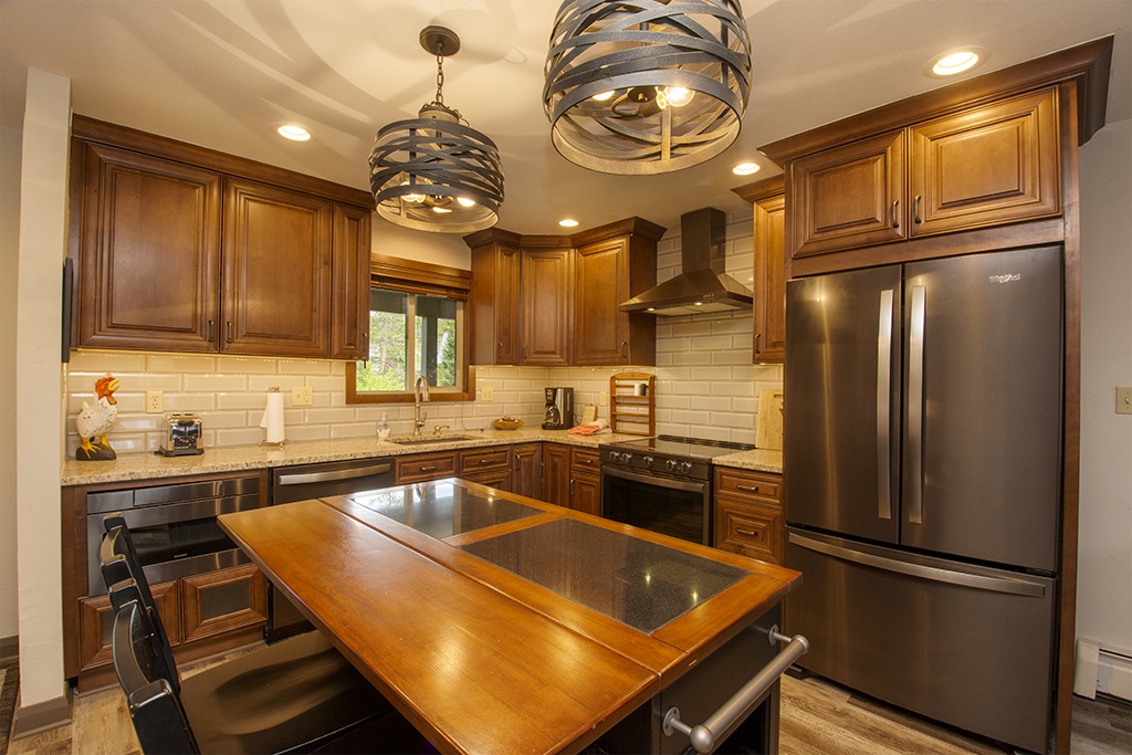 Your fully equipped gourmet kitchen features rich wood cabinetry, granite countertops, and stainless steel appliances for creating memorable meals together.