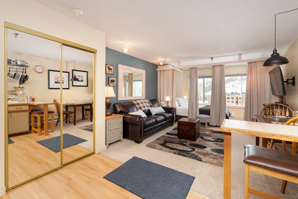 Relax in your spacious open-plan living area with cozy leather seating, modern kitchen access, and mountain views from your private balcony.