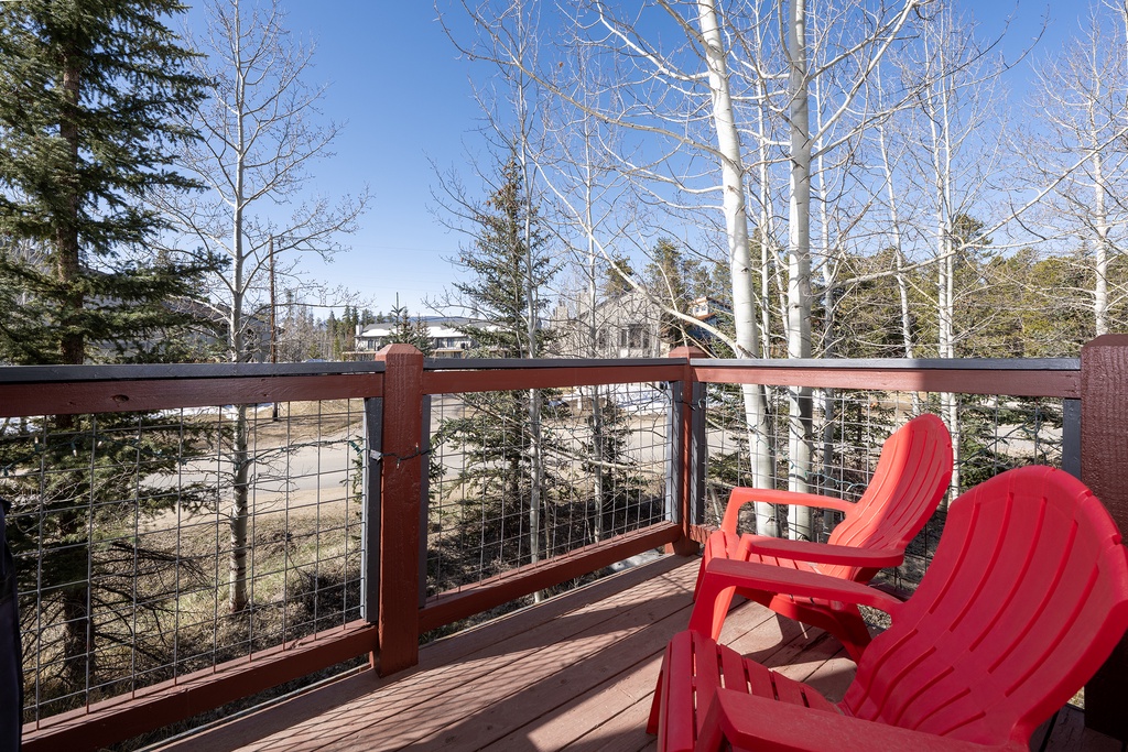 Relax in vibrant red Adirondack chairs on your private deck, surrounded by towering aspens and peaceful mountain views.