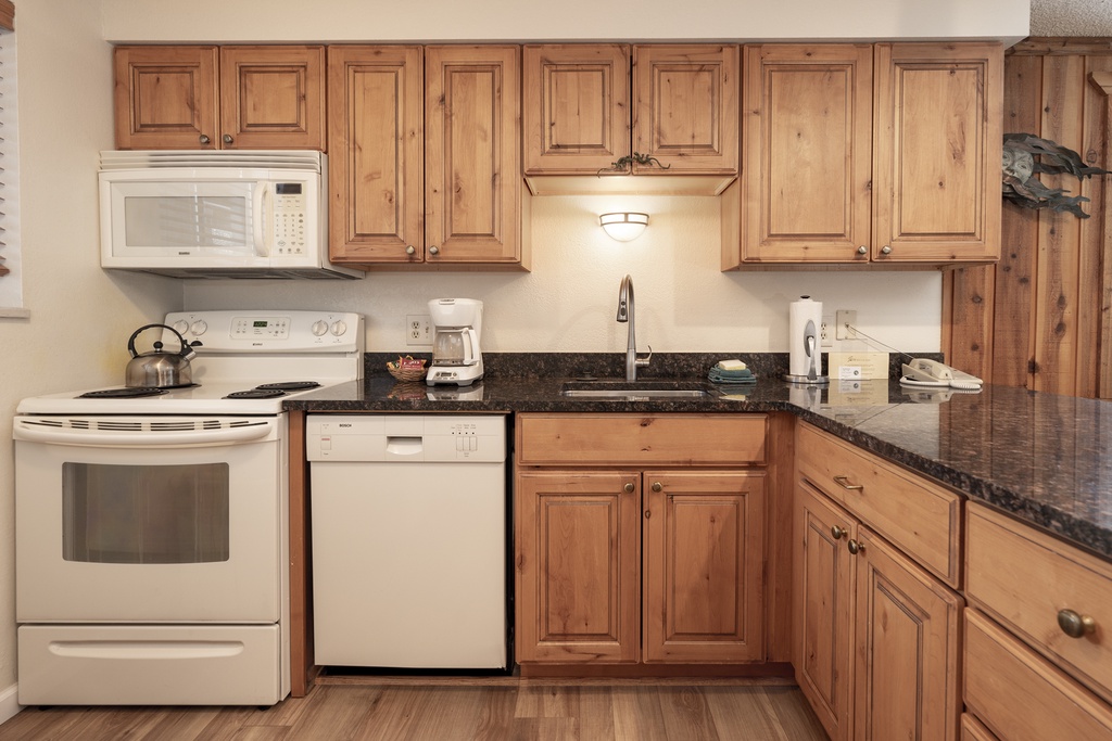 Your fully equipped kitchen awaits with warm wood cabinets, granite counters, and modern appliances to create memorable meals during your stay.
