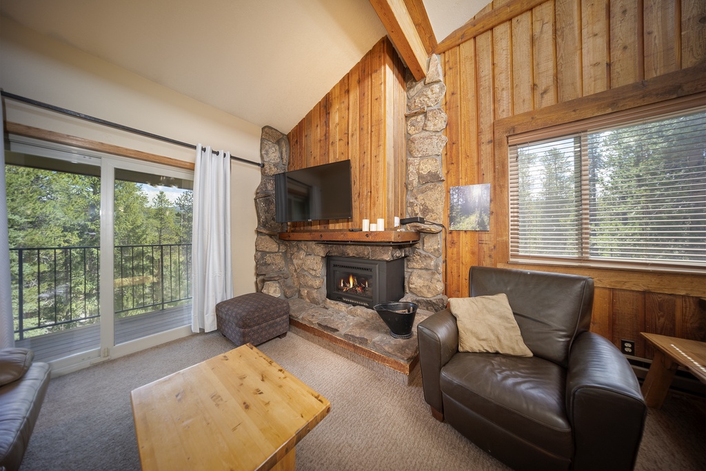 Cozy up by your crackling stone fireplace with forest views through the sliding doors.