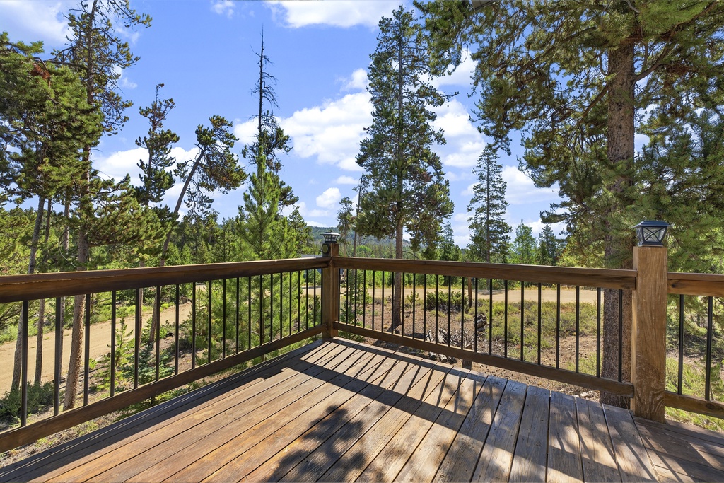 This spacious wooden deck offers a peaceful setting surrounded by tall pines and natural scenery—an ideal spot for your morning coffee or evening relaxation under open skies.