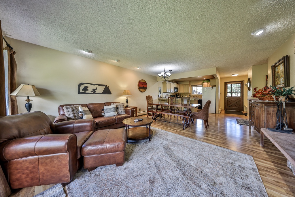 Relax in your spacious open-concept living area featuring rich leather seating, warm wood floors, and mountain cabin charm.