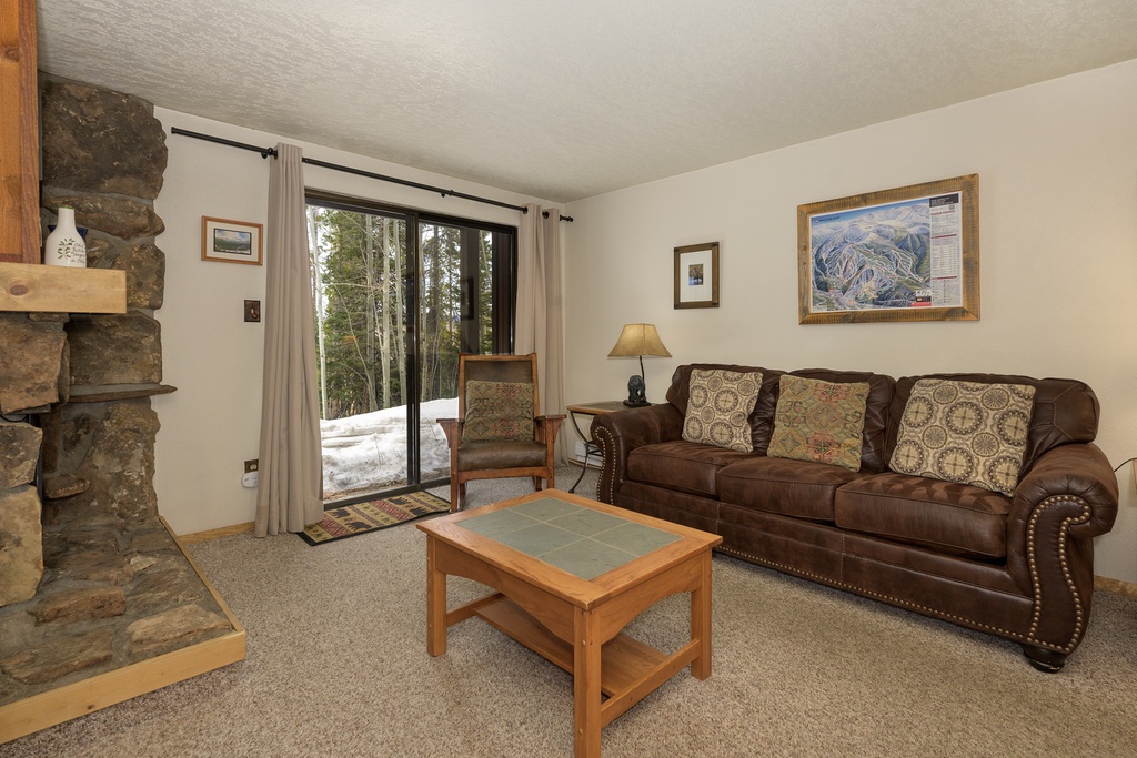 Cozy up in your welcoming living room featuring a stone fireplace and plush leather sofa, perfect for relaxing after mountain adventures.