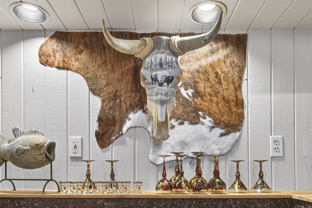 Unique rustic decor welcomes you with a striking longhorn hide accent and elegant barware display, blending mountain charm with distinctive style.