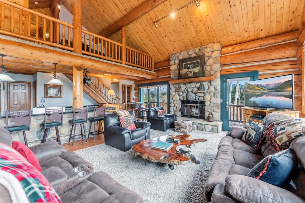 Cozy up in this stunning log cabin great room with soaring ceilings, stone fireplace, and plush seating perfect for mountain getaway memories.