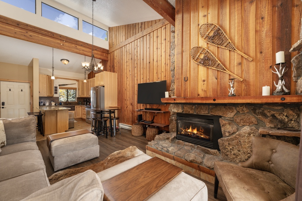 Cozy up by your crackling stone fireplace while snowshoes hang overhead, creating the perfect mountain retreat atmosphere for your alpine getaway.
