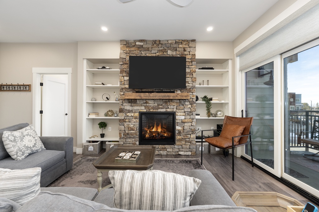 Unwind in your stylish living room where a crackling stone fireplace and cozy seating create the perfect atmosphere for relaxation.