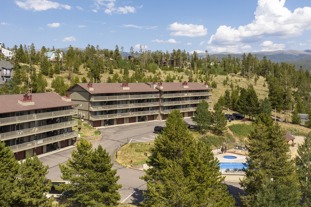 Nestled among towering pines with majestic mountain vistas in the distance, this alpine property features convenient parking and a refreshing outdoor pool surrounded by natural forest scenery.