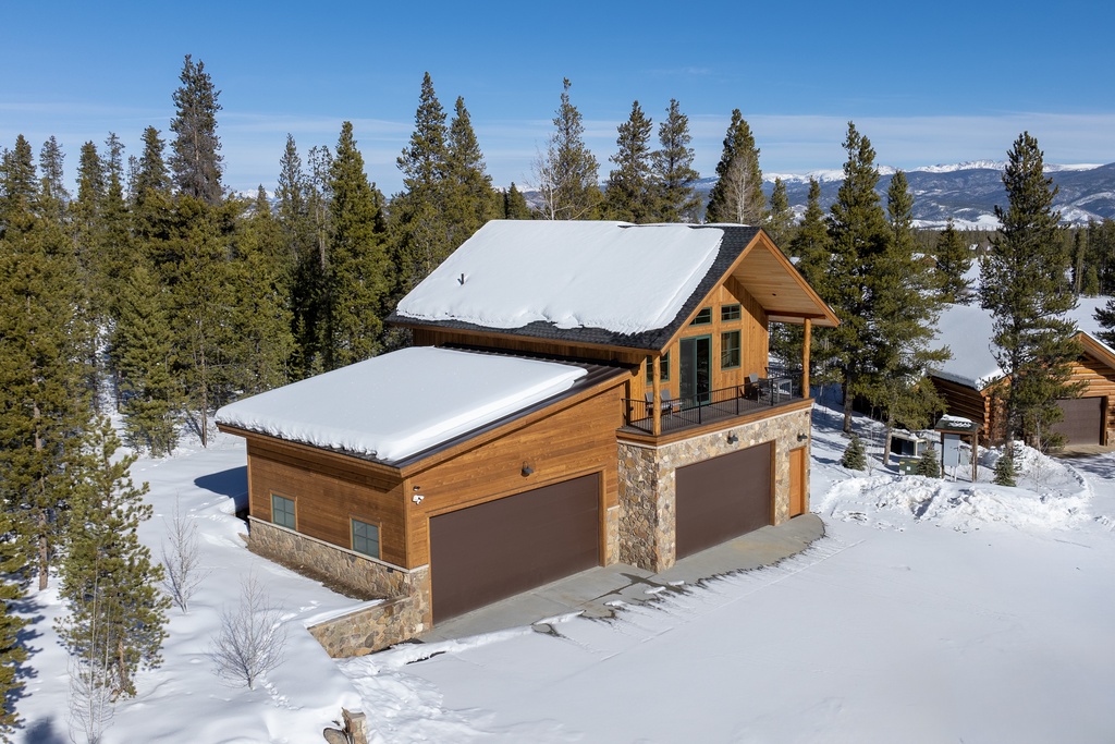 Mountain retreat property nestled among snow-covered evergreens with stunning alpine backdrop and winter wonderland setting.