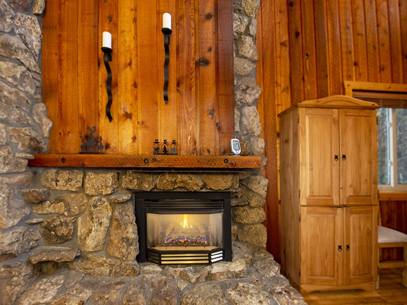 Cozy up by the rustic stone fireplace, surrounded by warm wood paneling that creates the perfect mountain retreat atmosphere.