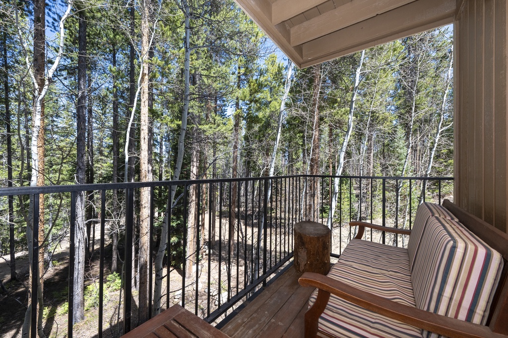 Relax on your private balcony surrounded by towering forest trees, where the peaceful woodland setting creates the perfect retreat.