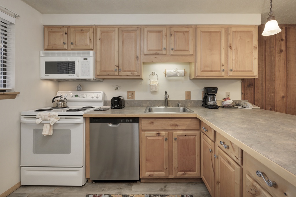 Your fully equipped kitchen awaits with warm wood cabinets, modern appliances, and everything needed for home-cooked meals during your stay.