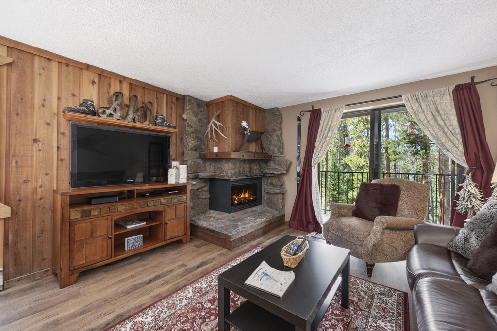 Cozy up in your living room with a crackling stone fireplace, large TV, and comfortable seating overlooking the treetops.