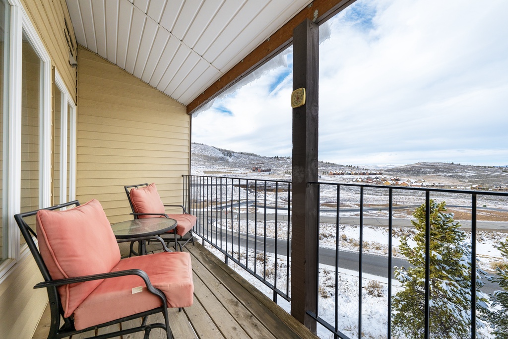 Relax on your private covered balcony at Mountainside Unit B-8 with panoramic winter mountain views and comfortable seating for morning coffee or evening unwind.
