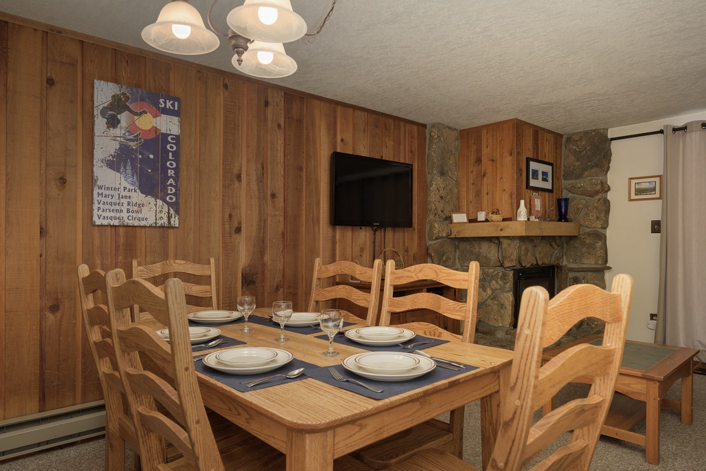 Gather around your cozy dining table, perfectly set for memorable meals beneath warm pendant lights and rustic wood paneling.