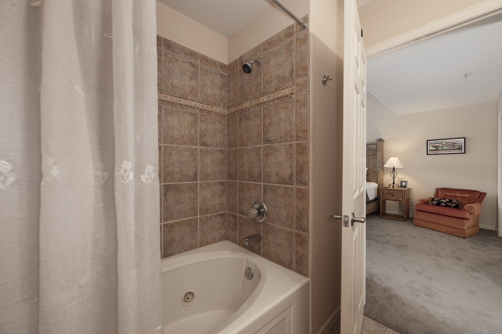 Step into your private bathroom featuring elegant tiled walls and a relaxing tub-shower combo, perfect for unwinding after exploring.