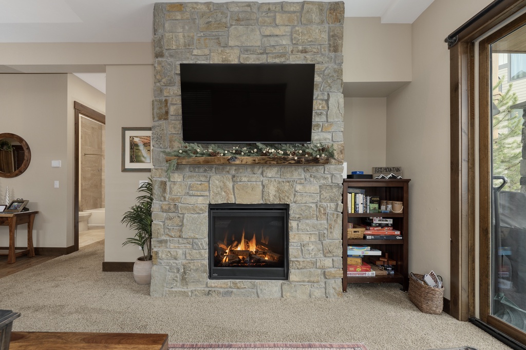 Cozy up by your stone fireplace while watching your favorite shows on the mounted TV in this inviting living space.