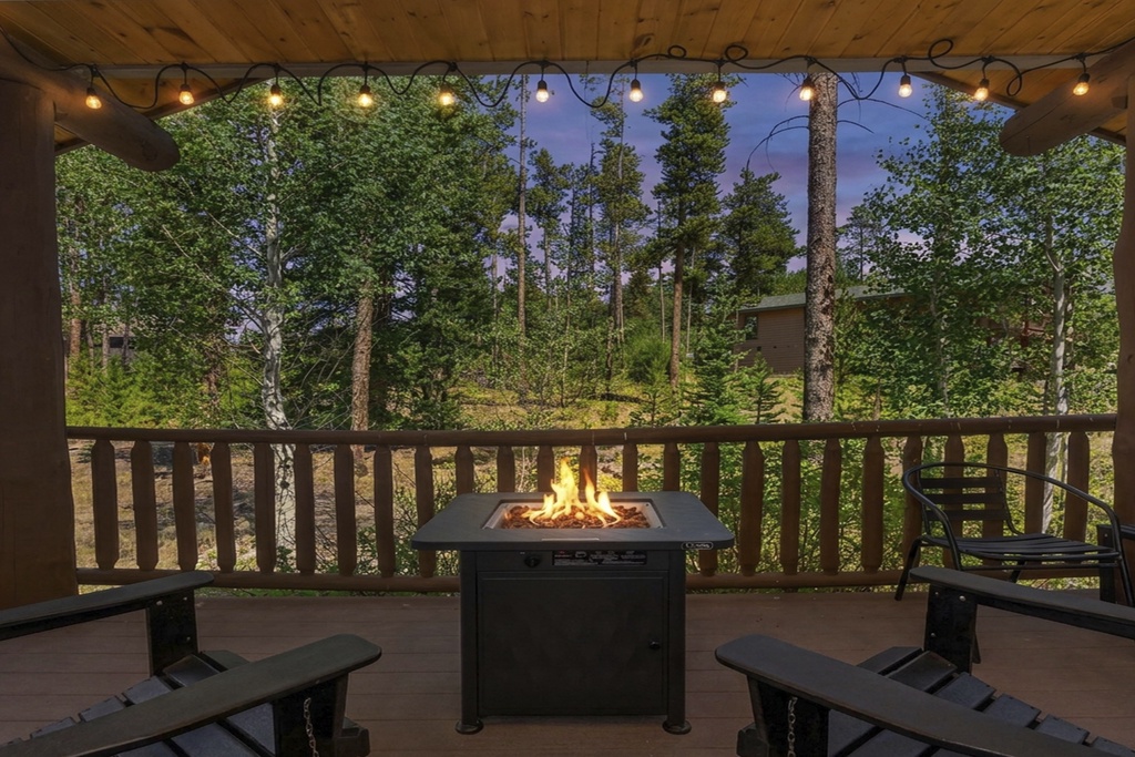 Gather under twinkling lights on your private covered deck, where a crackling fire pit invites cozy evening conversations surrounded by towering pines and mountain tranquility.