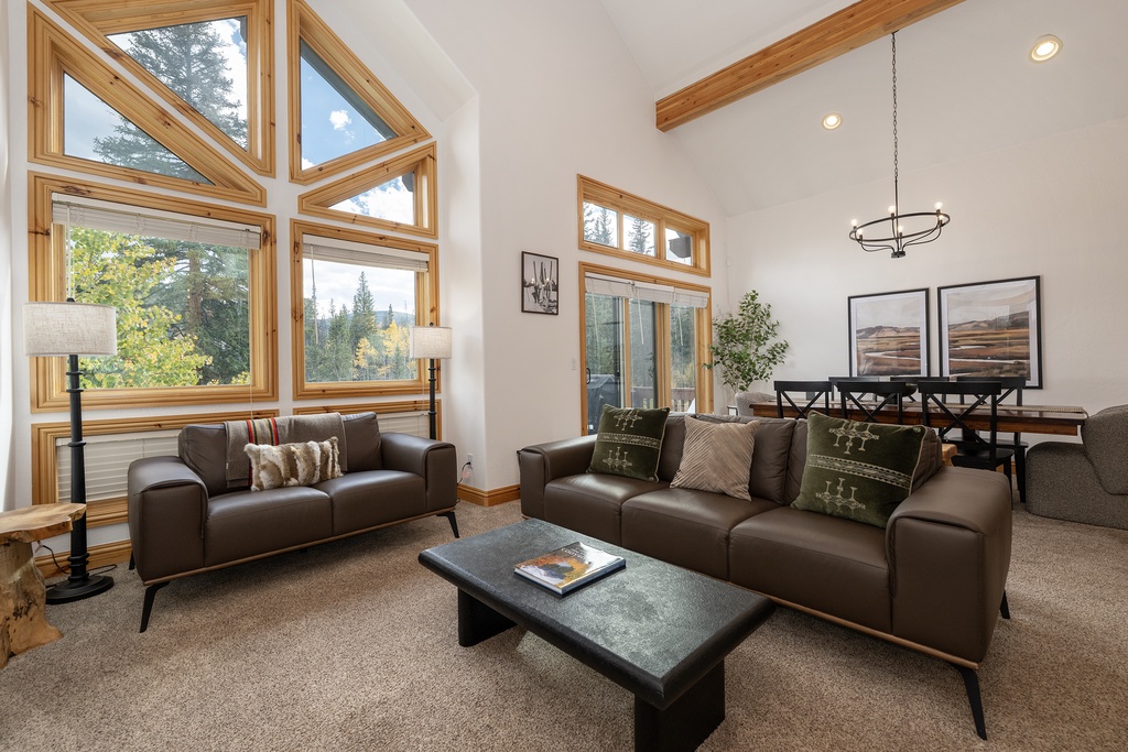 Unwind in your bright living space with soaring ceilings, warm wood beams, and windows framing stunning forest views.