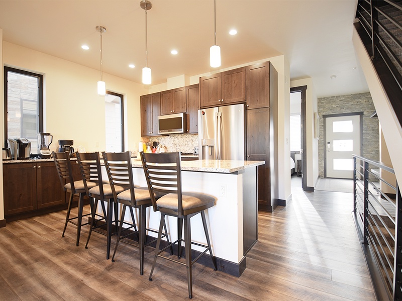 Your sleek kitchen features warm wood cabinetry, modern appliances, and a spacious island perfect for morning coffee or evening meals together.