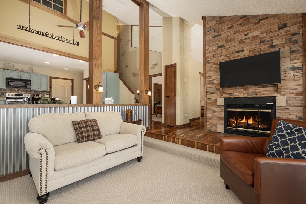 Cozy up by your crackling fireplace in this stunning living room featuring soaring ceilings and warm wood accents.