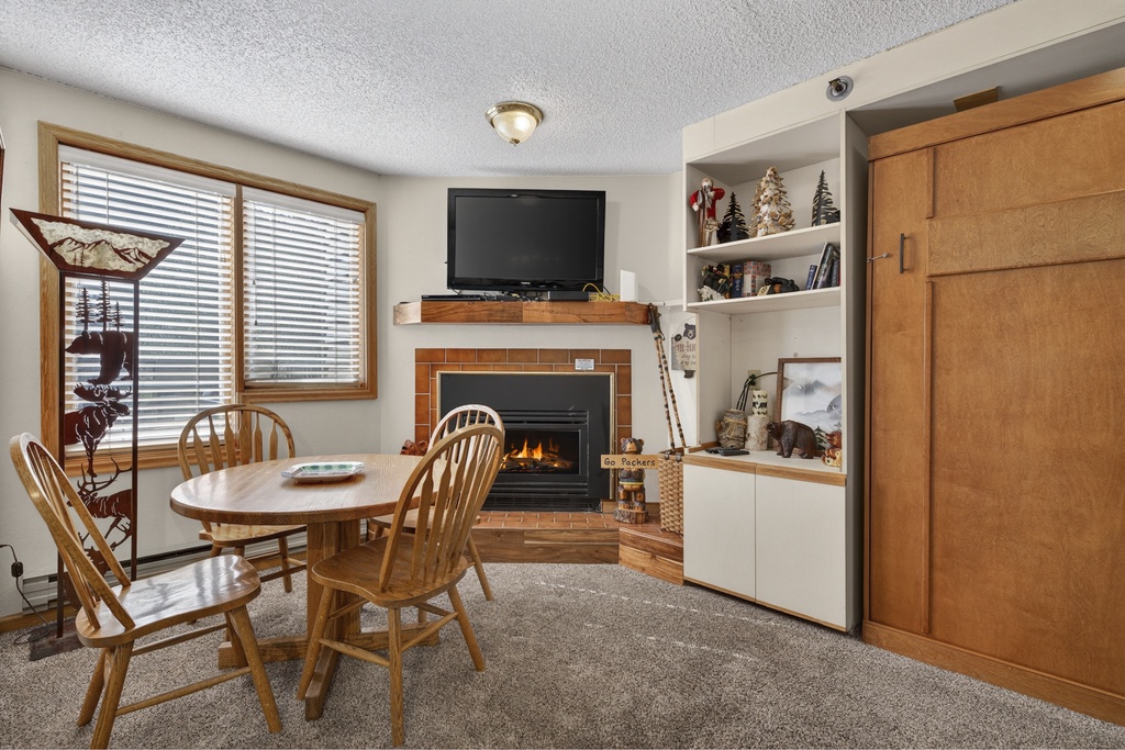 Gather around this cozy dining space where a warm fireplace sets the perfect ambiance for your meals and evening conversations, with entertainment and comfort at your fingertips.