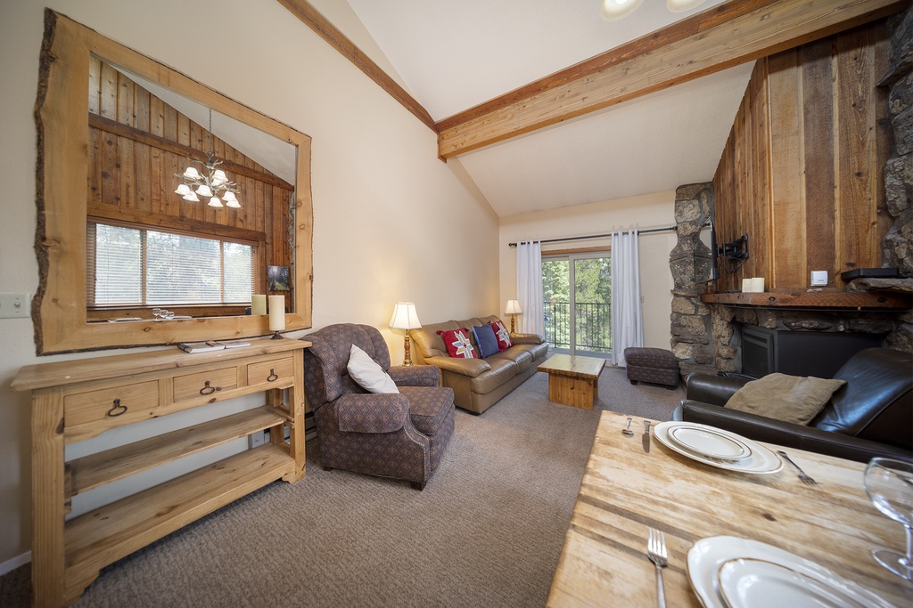 Unwind in your cozy mountain retreat with exposed beams, stone fireplace, and comfortable seating where rustic charm meets modern comfort.