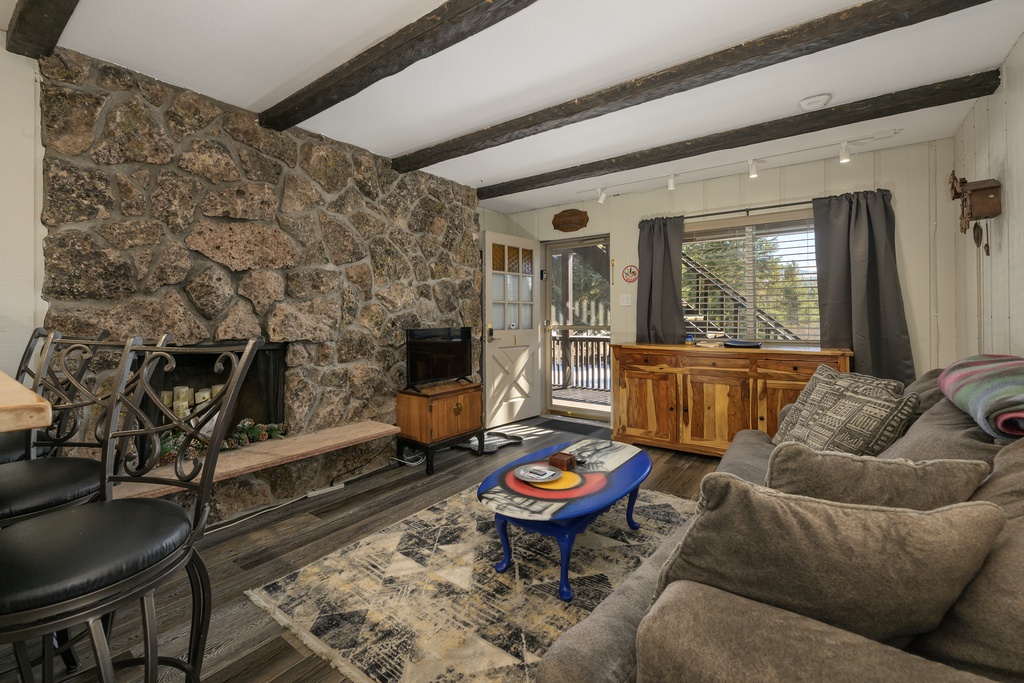 Relax by your stone fireplace while rustic beams frame cozy moments in this charming living space.