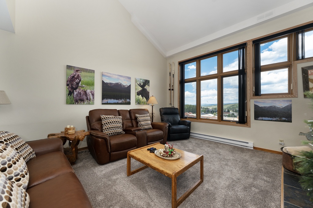 Relax in your cozy living room with leather seating and stunning mountain views through large windows.