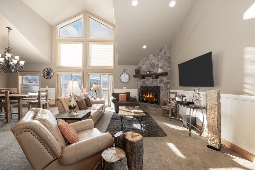 Unwind in this elegant living room where soaring ceilings and a crackling stone fireplace create the perfect mountain retreat atmosphere.