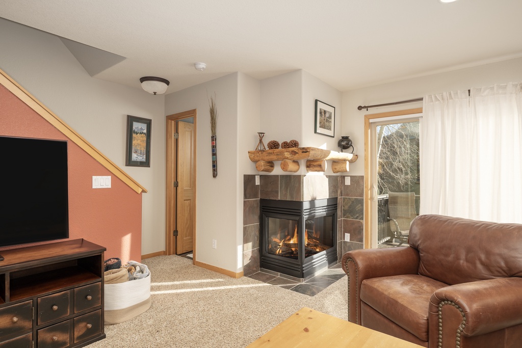Curl up in your cozy living room where a crackling fireplace and plush leather seating create the perfect retreat after mountain adventures.