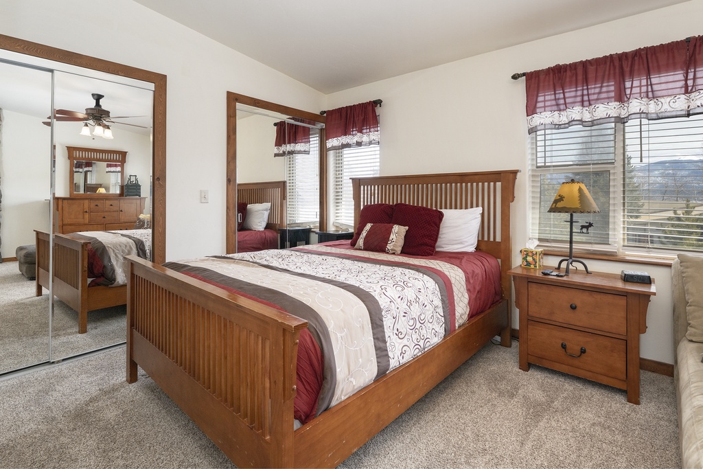 Sink into Granby Lake Shore Estates Townhome 5 cozy bedroom's warm wood furniture and rich burgundy accents. Natural light streams through your windows while comfortable bedding awaits your restful nights.