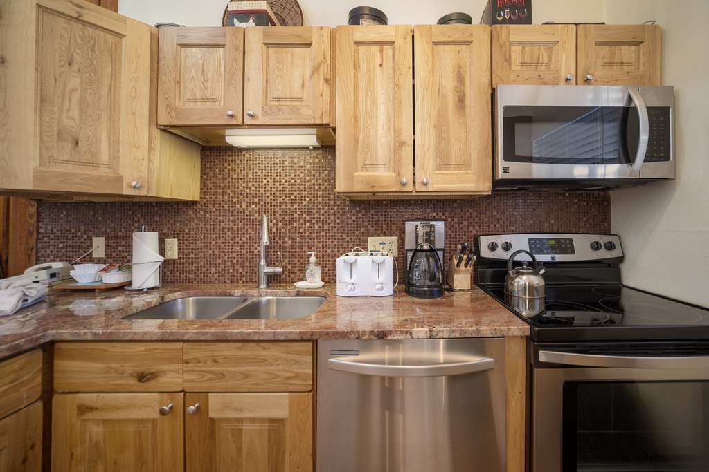 Your fully equipped kitchen features warm wood cabinets, granite counters, and modern appliances perfect for preparing meals.