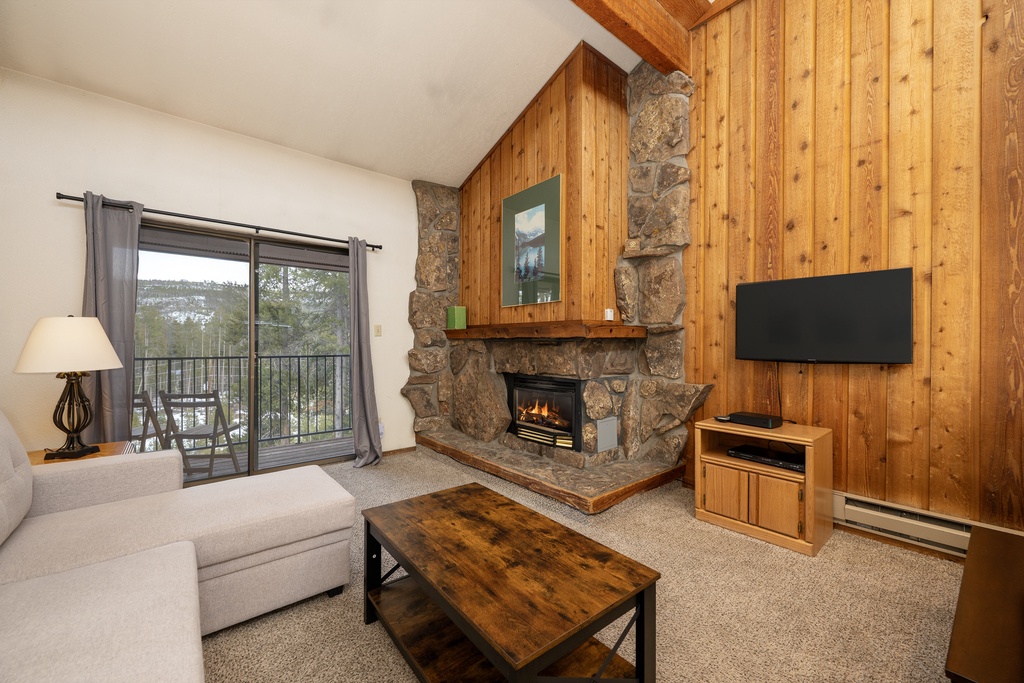 Cozy up in your mountain retreat with a crackling stone fireplace, warm wood accents, and peaceful valley views from your private balcony.