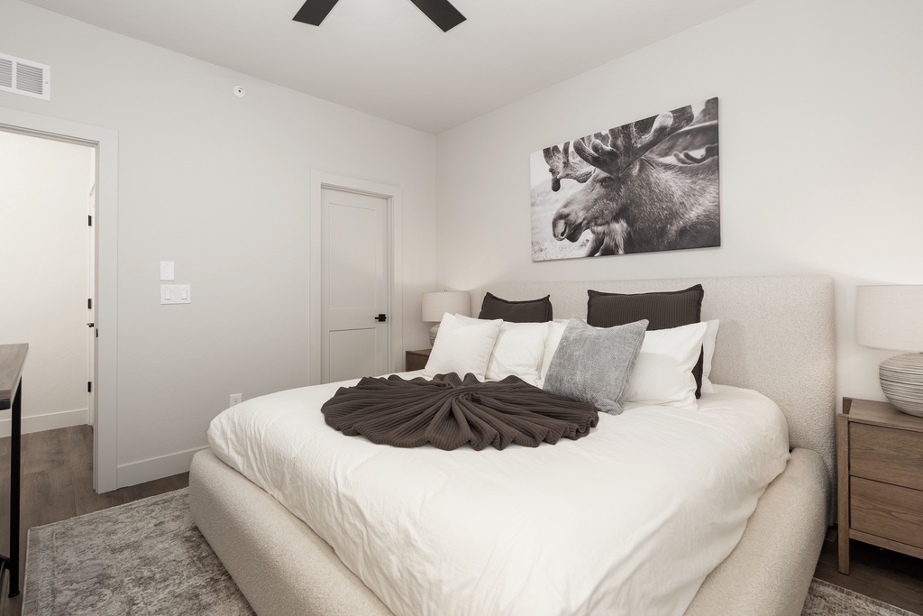 Sink into your plush bed with crisp white linens and stylish accents, where peaceful sleep awaits in this serene sanctuary.