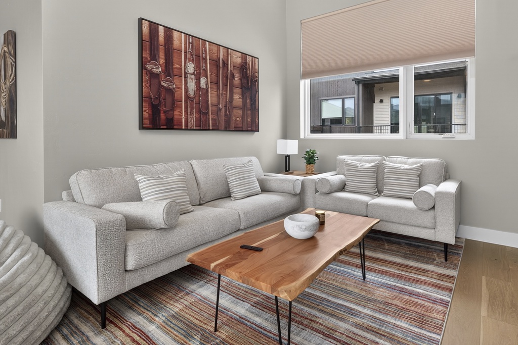 Sink into plush gray sofas and unwind in your bright, contemporary living space with warm wood accents and city views.