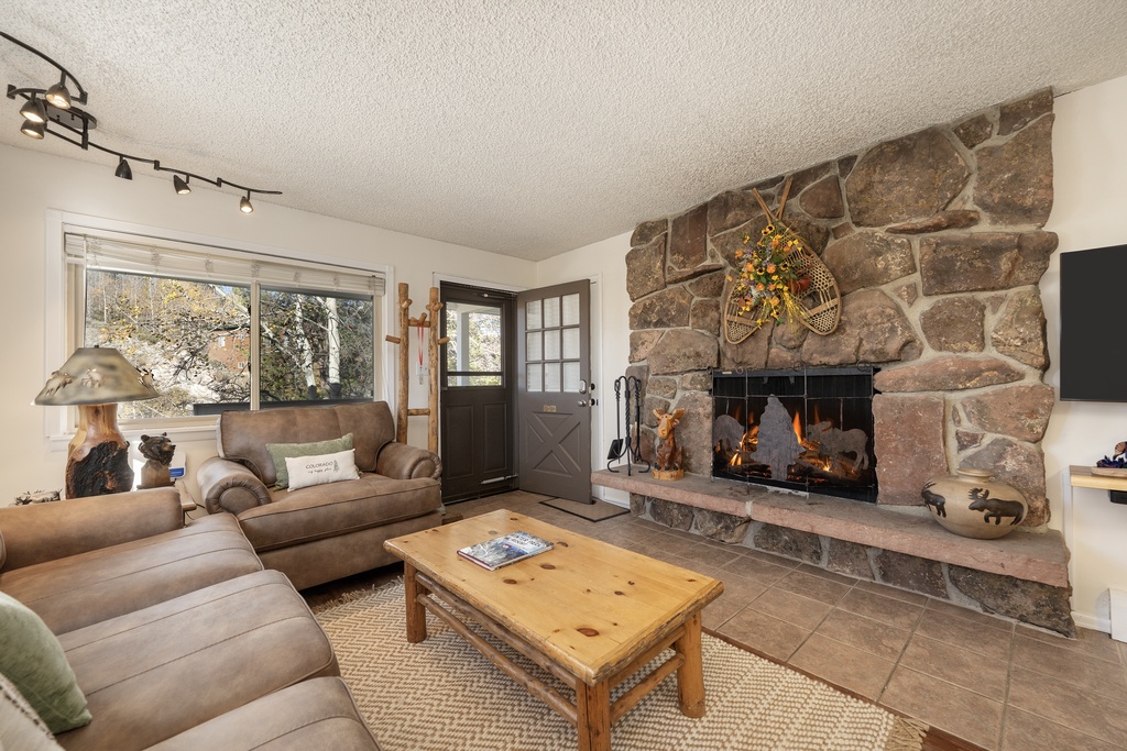 Relax in your cozy living room featuring a stunning stone fireplace and comfortable seating perfect for evening gatherings.