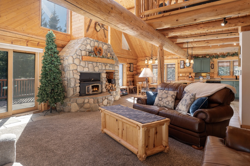 Relax in this cozy living room where rustic wood beams meet a stunning stone fireplace, creating your perfect mountain retreat atmosphere.