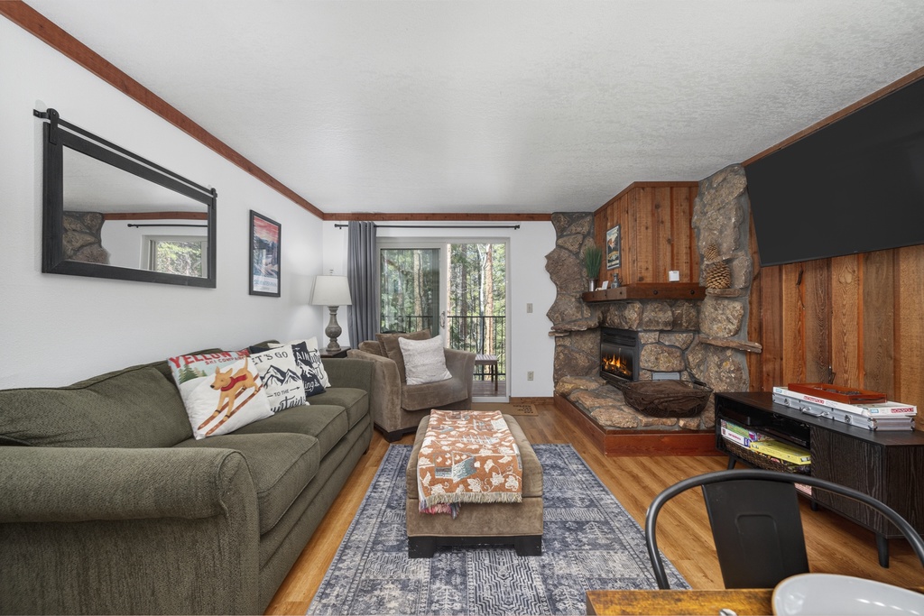 Cozy up by your crackling stone fireplace in this inviting living room, where warm wood accents and comfortable seating create the perfect mountain retreat atmosphere.