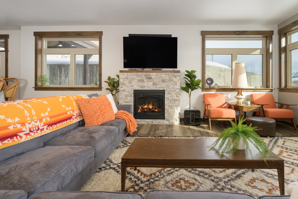Cozy up by your stone fireplace in this bright living space with plush seating and warm natural light streaming through oversized windows.